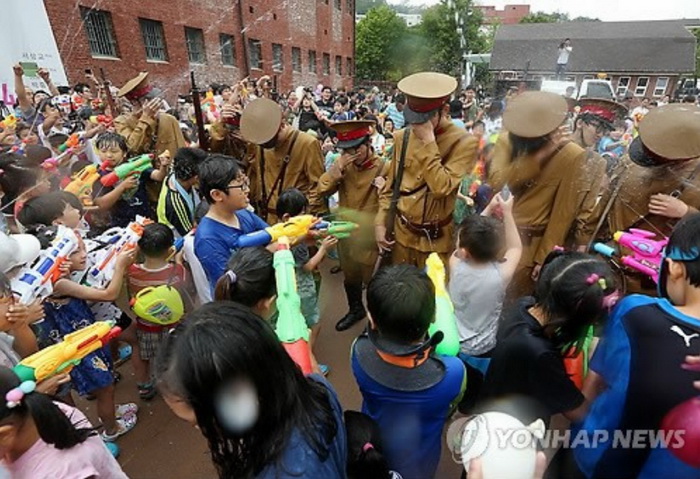 光复节纪念活动组织者穿上“鬼子”服装，参加活动的儿童用水枪“打鬼子”庆祝光复节(网页截图)