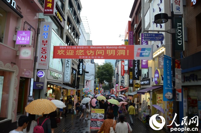 国庆黄金周期间，冒雨在明洞街头购物的中国游客们。（摄影：裴埈基）