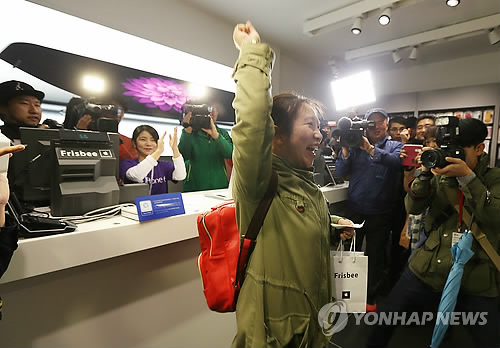 图为位于首尔明洞的苹果专卖店Frisbee第一个买到iPhone6的顾客在拿到手机后举手欢呼。