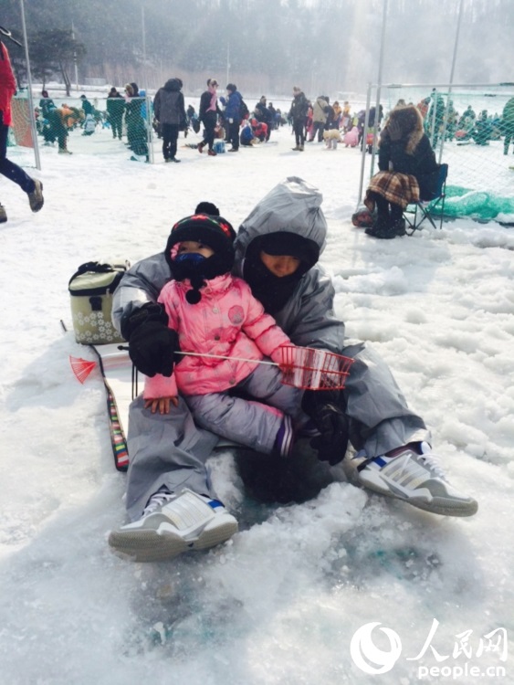 在江原道平昌举行的平昌鳟鱼节现场，一家人正在体验冰钓。