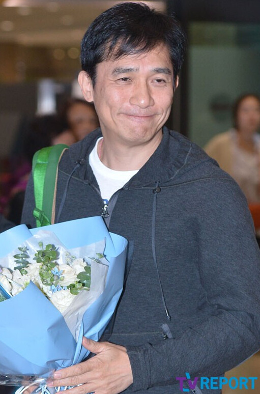 梁朝伟现身韩国机场受追捧 收到鲜花露笑容【组图】