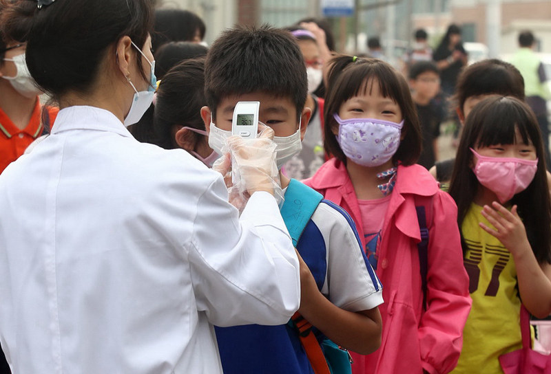 6月15日，在韩国首尔以南平泽的一所刚刚复课的小学，医务人员为学生测量体温。