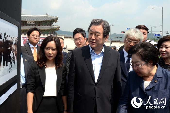 韩国执政党新国家党党首金武星（中）、国会议员金乙东（右）、人民网韩国公司负责人周玉波（左）在观看图片展。（摄影：张悦）