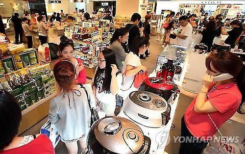 资料图片：中国游客们在韩国免税店选购电饭煲。