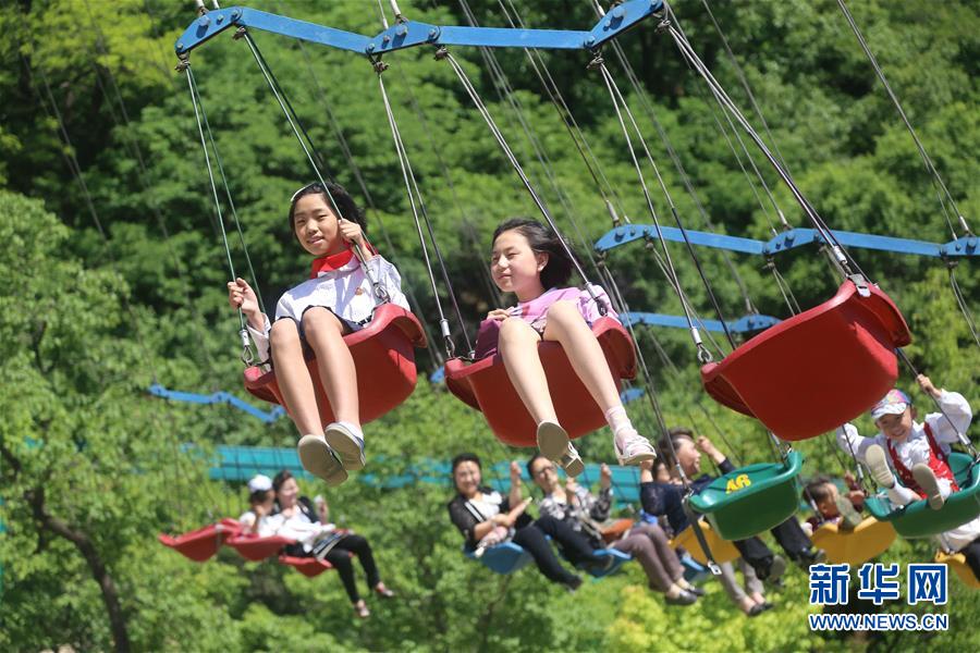  6月1日，在朝鲜平壤大城山游乐园，孩子们体验游乐项目。