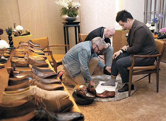 国外工匠正在为一位中年男性制作手工定制皮鞋（图片来源：中央日报）