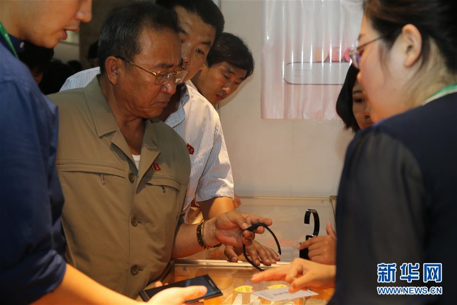 在朝鲜首都平壤，朝鲜顾客在一家展台前了解智能手环。