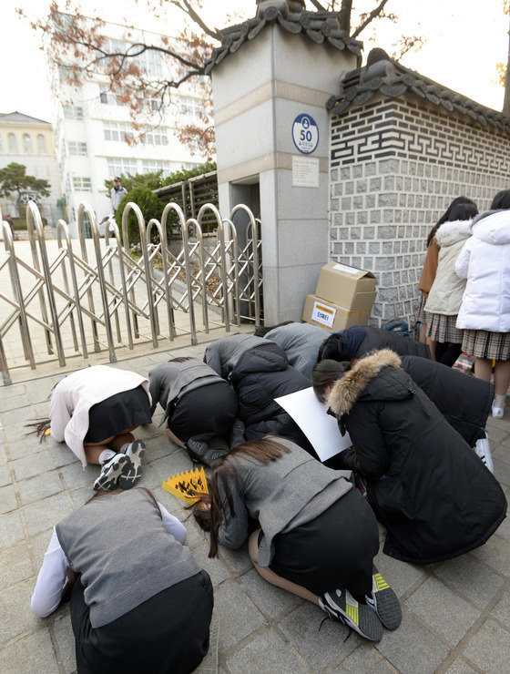 低年級學生通過“跪拜”的方式為考生加油。