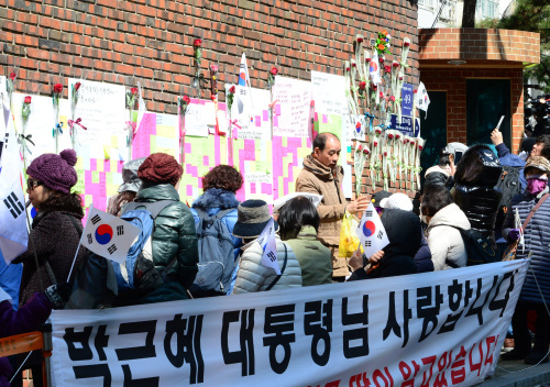 朴槿惠的支持者在其私宅外拉應援橫幅，並將鮮花放在牆外。