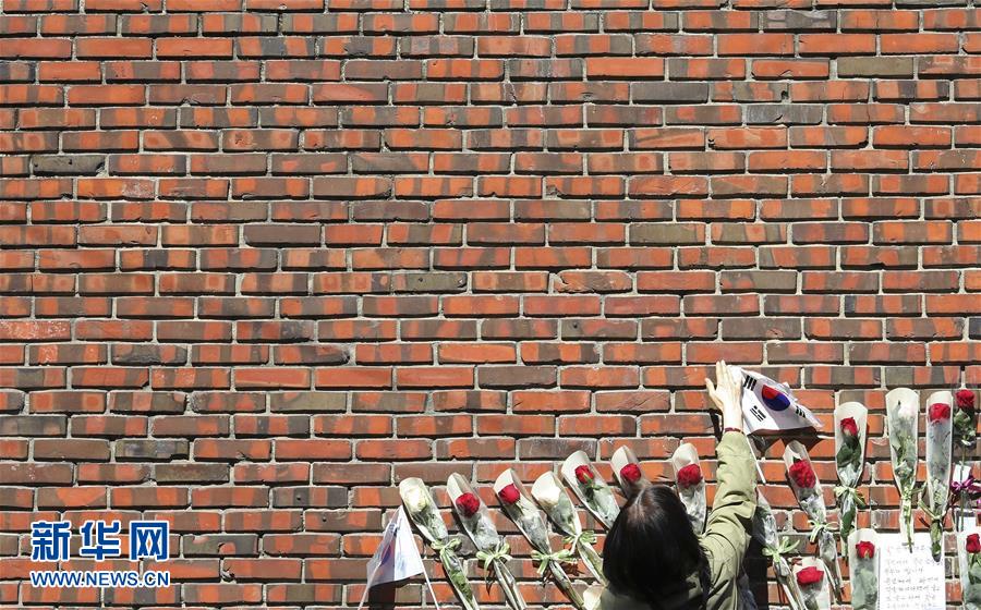 3月15日，在韓國首爾，一名韓國前總統朴槿惠的支持者將國旗放在朴槿惠私宅牆外。