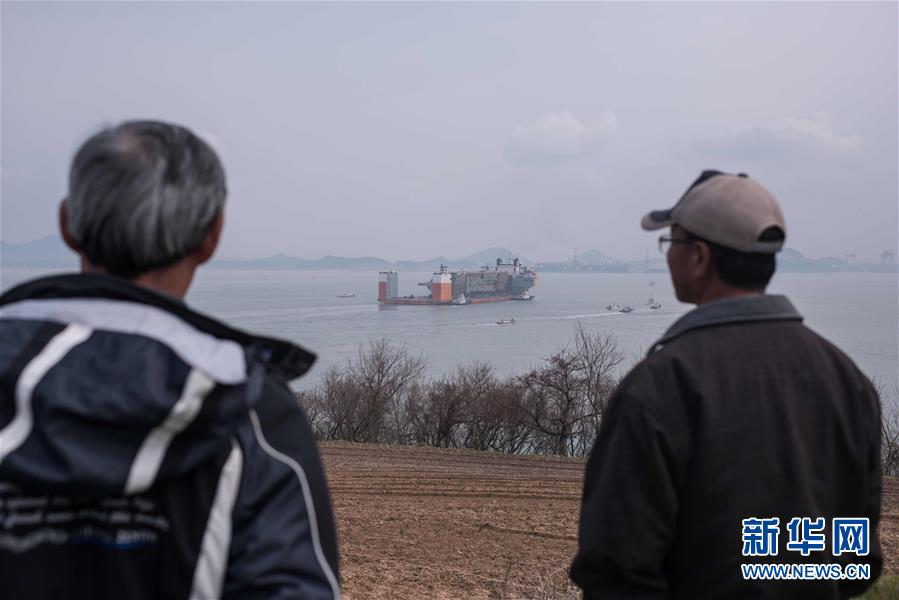 3月31日，人們在遠處觀看載有韓國“世越”號沉船船體的半潛船抵達木浦新港。