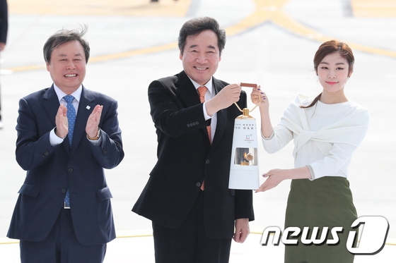 韓國國務總理李洛淵（中）與平昌冬奧會宣傳大使金妍兒（右）手持聖火火種燈。