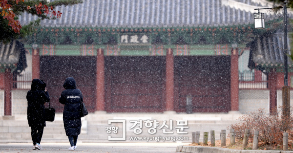 首爾市民在慶熙宮小路上散步，欣賞初雪美景。