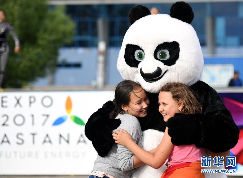 這是2017年6月5日，在哈薩克斯坦首都阿斯塔納一個游樂場，兒童和舞蹈團的熊貓卡通形象互動。當日，由哈薩克斯坦歐亞大學在讀學生組成的薩姆魯格舞蹈團在阿斯塔納的游樂場為市民表演節目。新華社記者 吳曉凌 攝