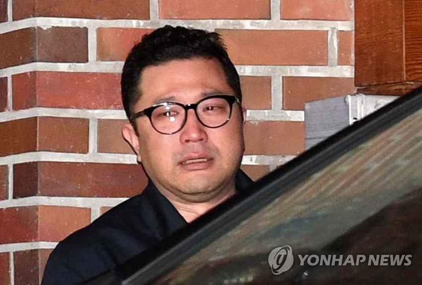 韓國前總統李明博在私邸被檢方逮捕，其子李時炯眼中噙滿淚水目送父親離開。（圖片來源：韓聯社）