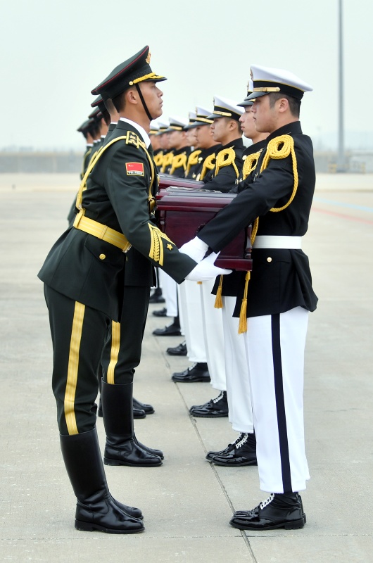 3月28日，在韓國仁川國際機場，韓方（右）向中方禮兵移交中國人民志願軍烈士遺骸。新華社發（韓國國防部供圖）