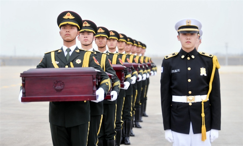 3月28日，在韓國仁川國際機場，中方禮兵（左）從韓方手中接過中國人民志願軍烈士遺骸。新華社發（韓國國防部供圖）