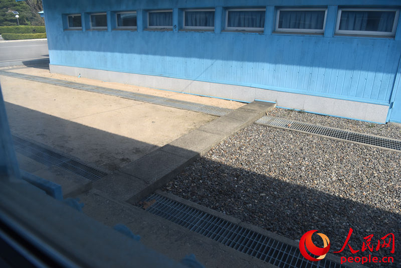 穿過藍房子的水泥坎為軍事分界線，砂石地一側為韓國，水泥地一側為朝鮮。夏雪攝