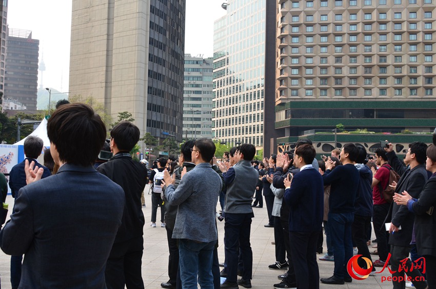 位於首爾市中心首爾廣場的戶外大屏全程直播韓朝首腦會談。圖為當兩位領導人在軍事分界線握手時，民眾集體鼓掌慶祝這一歷史性的時刻。郝萍攝