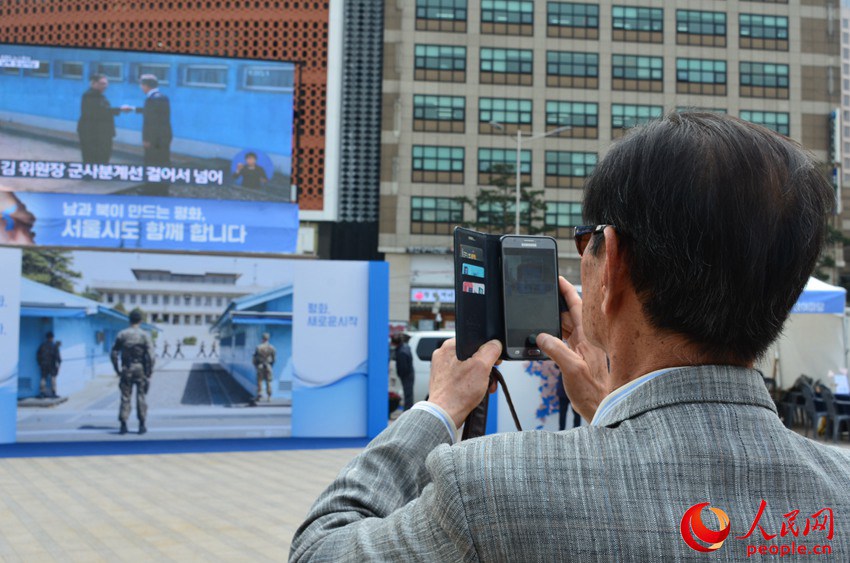 位於首爾市中心首爾廣場的戶外大屏全程直播韓朝首腦會談。圖為一位首爾市民用手機拍攝直播畫面。郝萍攝