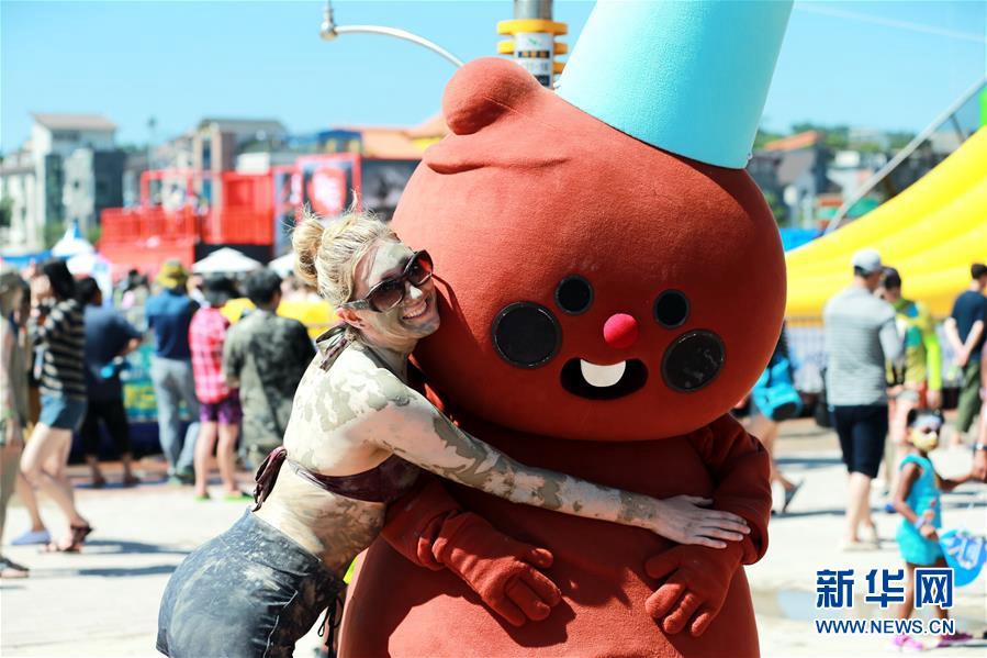 7月14日，游客在韓國保寧市舉行的保寧泥漿節上和吉祥物人偶合影。新華社記者 王婧嬙 攝