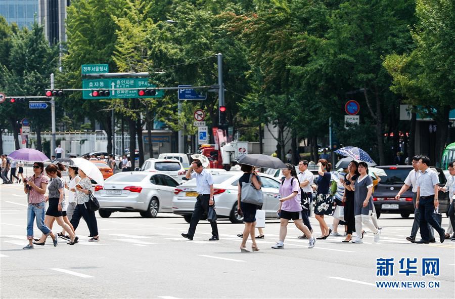 8月3日，在韓國首爾，人們手持遮陽傘出行。新華社記者 王婧嬙 攝