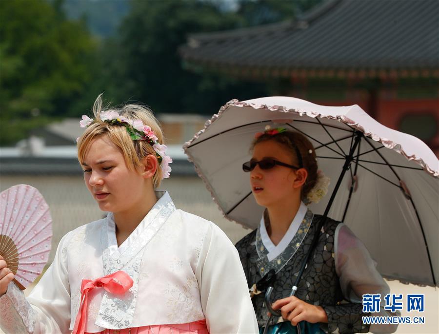8月3日，在韓國首爾，游客手持遮陽傘和扇子游覽景福宮。新華社記者 王婧嬙 攝