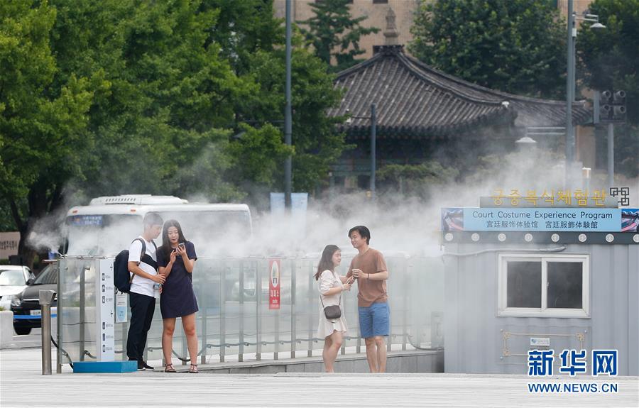 8月3日，在韓國首爾光化門廣場，人們享受水霧的清涼。新華社記者 王婧嬙 攝