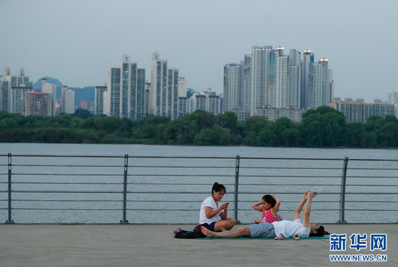 8月3日，一家人在韓國首爾汝矣島漢江公園裡納涼。新華社記者 王婧嬙 攝