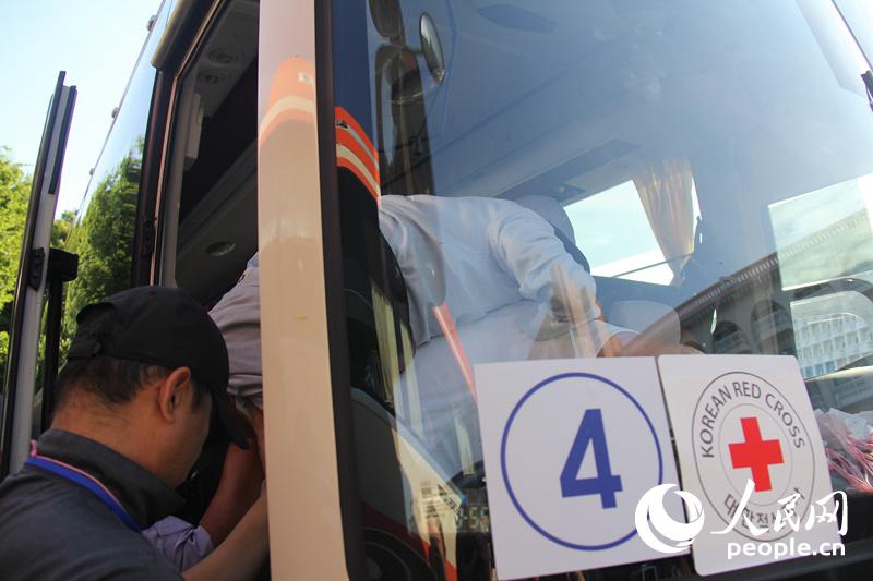 一位韓方探親老人年事已高、腿腳不便，隻得由工作人員背上車。 人民網記者 陳尚文攝