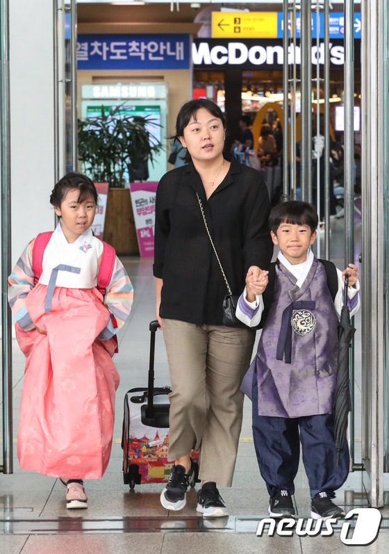 一位母親帶領兩名穿著韓服的小朋友正在進站上車。小朋友臉上挂滿燦爛笑容。（圖片來源：韓媒News1）