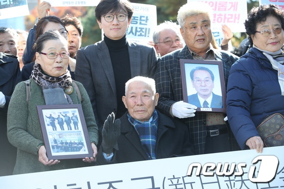 30日下午，二戰期間被日企強征的韓國勞工受害者抱著已離世受害者的遺像走進韓國高等法院。