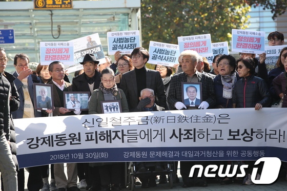 30日下午，二戰期間被日企強征的韓國勞工受害者抱著已離世受害者的遺像走進韓國高等法院。