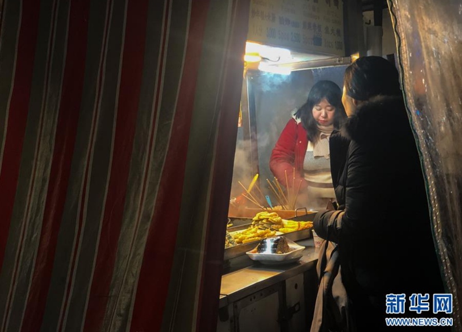 12月28日，人们在韩国首尔新村附近的一家路边小吃摊享用热气腾腾的美食。 新华社记者 王婧嫱 摄