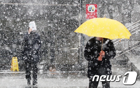 19日在首爾光化門交通崗處，市民們冒著大雪去上班。