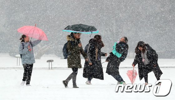 19日在首爾汝矣島的國會草坪上，學生們打著雨傘在雪中嬉戲玩耍。