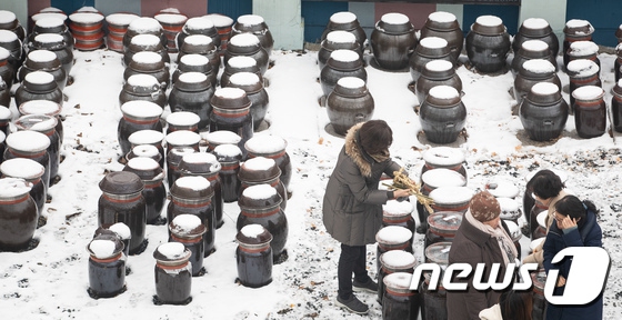 19日在首爾創新園，大大小小的醬缸整整齊齊地擺放在地上，連同地面，醬缸的蓋子上也覆蓋著一層積雪。一旁的人們正聚在一起研究制作美味的傳統醬。