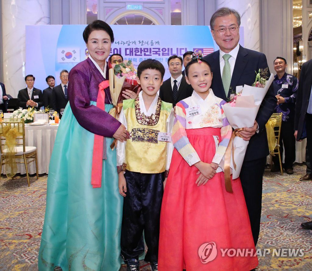 3月12日晚上，韓國總統文在寅（右一）出席在吉隆坡萬豪酒店舉行的馬來西亞各界韓人韓僑歡迎晚宴。圖為文在寅夫婦與花童合影留念。