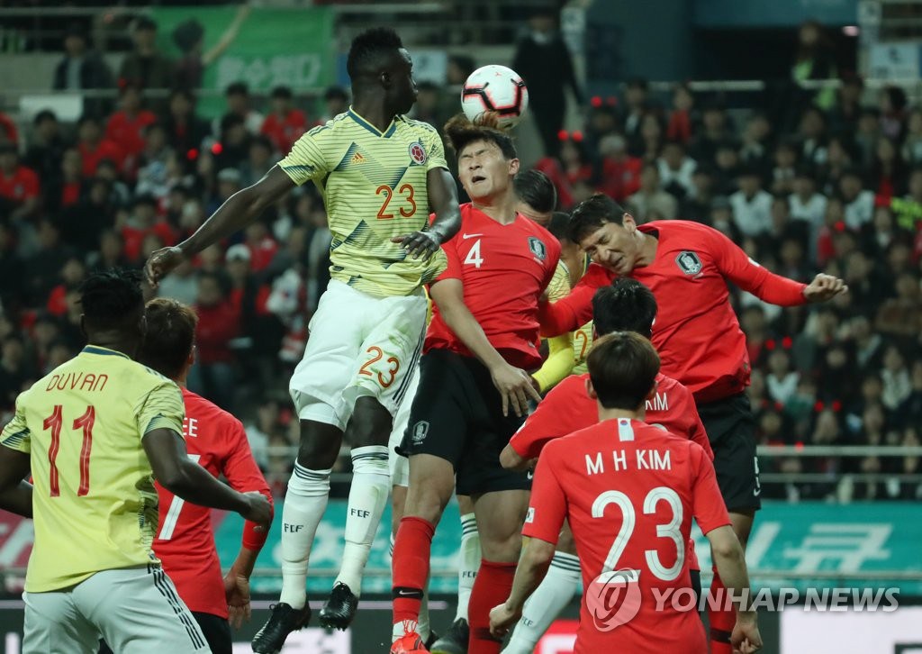 韓國球員金珉載與哥倫比亞球員戴維森·桑切斯搶奪高空球。