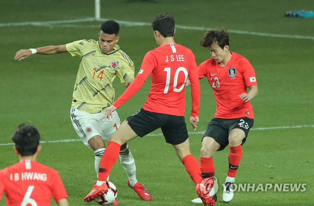 哥倫比亞球員迪亞茲試圖躲開韓國球員李在城和金文煥的守備，准備射球。