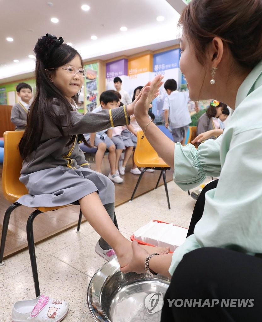 5月15日，在大邱市永新小學，老師給學生洗腳並擊掌。（圖片來源：韓聯社）