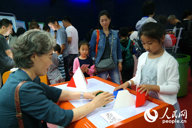 小學生在韓國釜山國家科學博物館館長高賢淑的指導下拼正四面體拼圖。汪璨攝