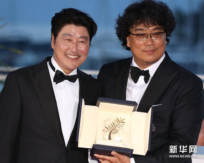 5月25日，在法國戛納，韓國導演奉俊昊（右）與演員宋康昊手捧金棕櫚獎杯出席拍照式。新華社記者 高靜 攝