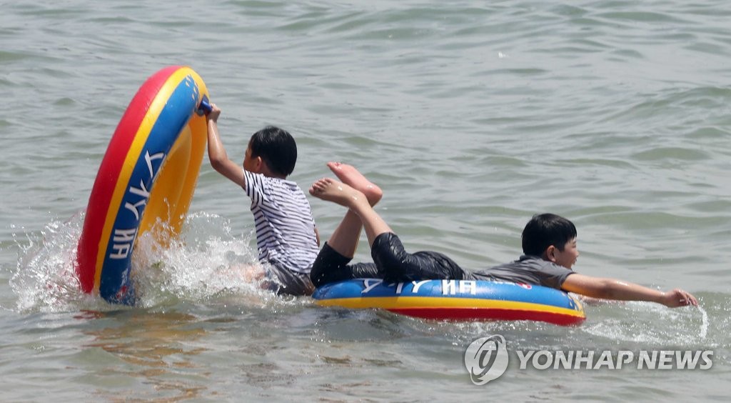 6月2日，在釜山海雲台海水浴場，兩名小朋友用大號游泳圈當作小船在海中漂浮玩耍。