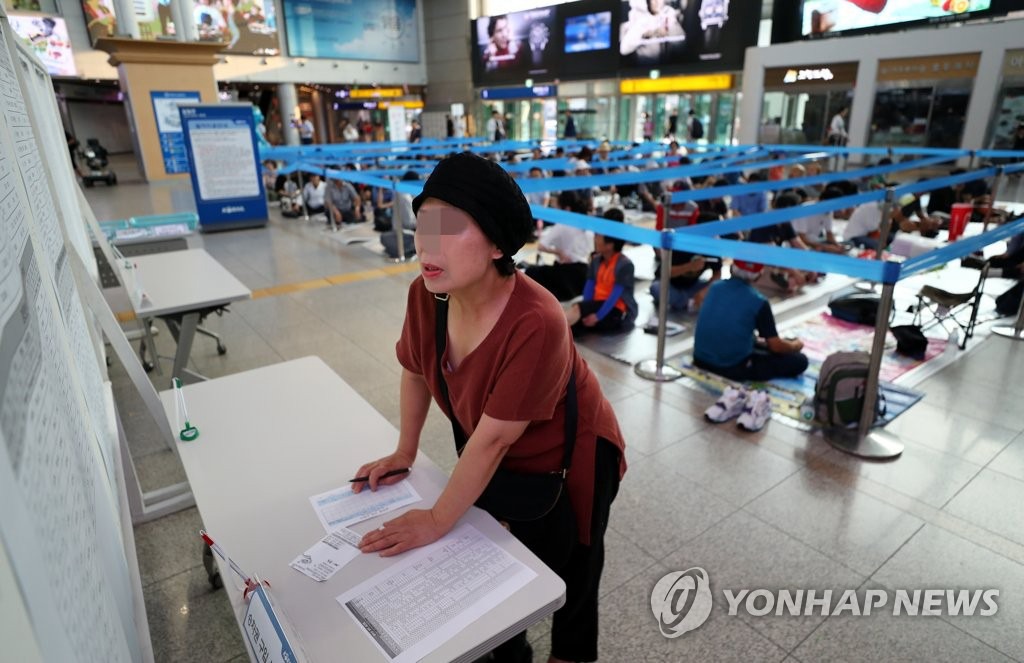 20日在首爾站，某市民正在填寫購票申請單。