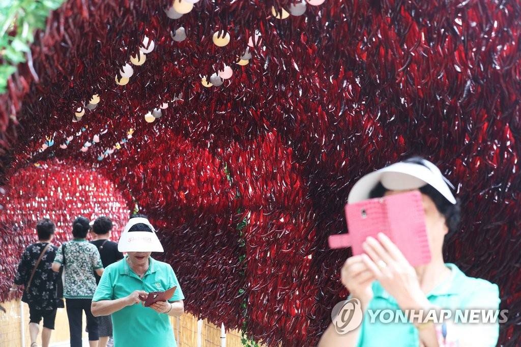 市民們站在“紅色隧道”下拍照。（圖片來源：韓聯社）