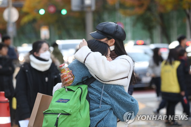 11月14日，在首爾一考點，一考生在進入考場前與家人相擁。 韓聯社