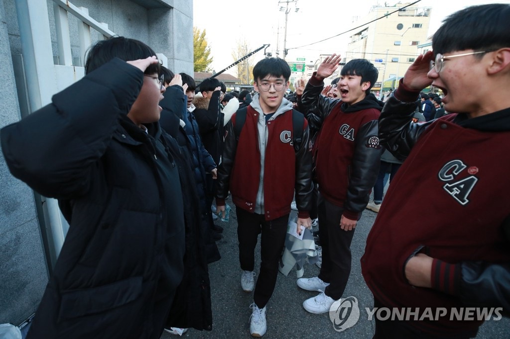 14日上午，首爾龍山高中考場考生們在后輩們的敬禮下走向考場。