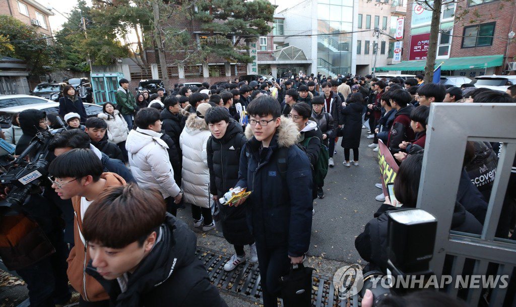 14日上午，首爾鐘路區景福高中前，一位考生在后輩的加油聲中進入考場。