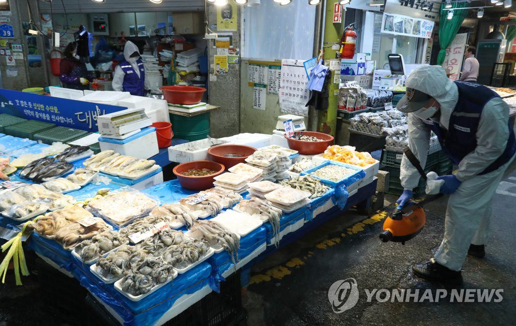 24日，在首爾麻浦區的望遠市場，防疫人員正在進行消毒防疫工作。